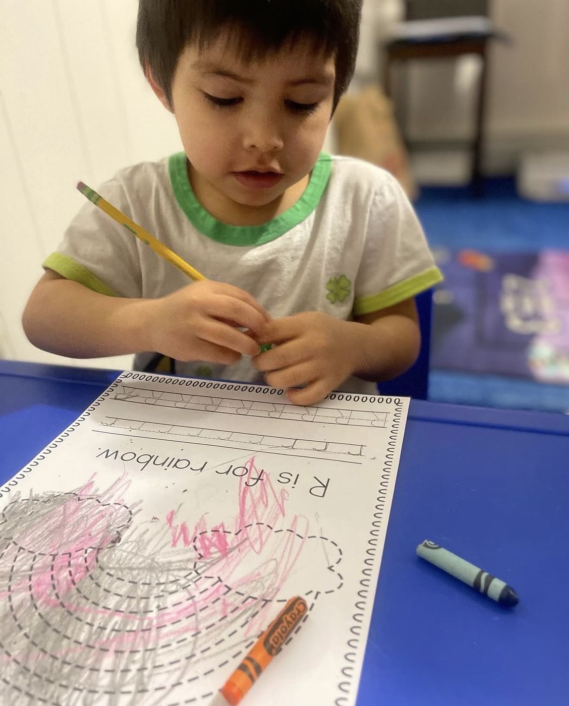 Preschooler coloring an R is for Rainbow worksheet