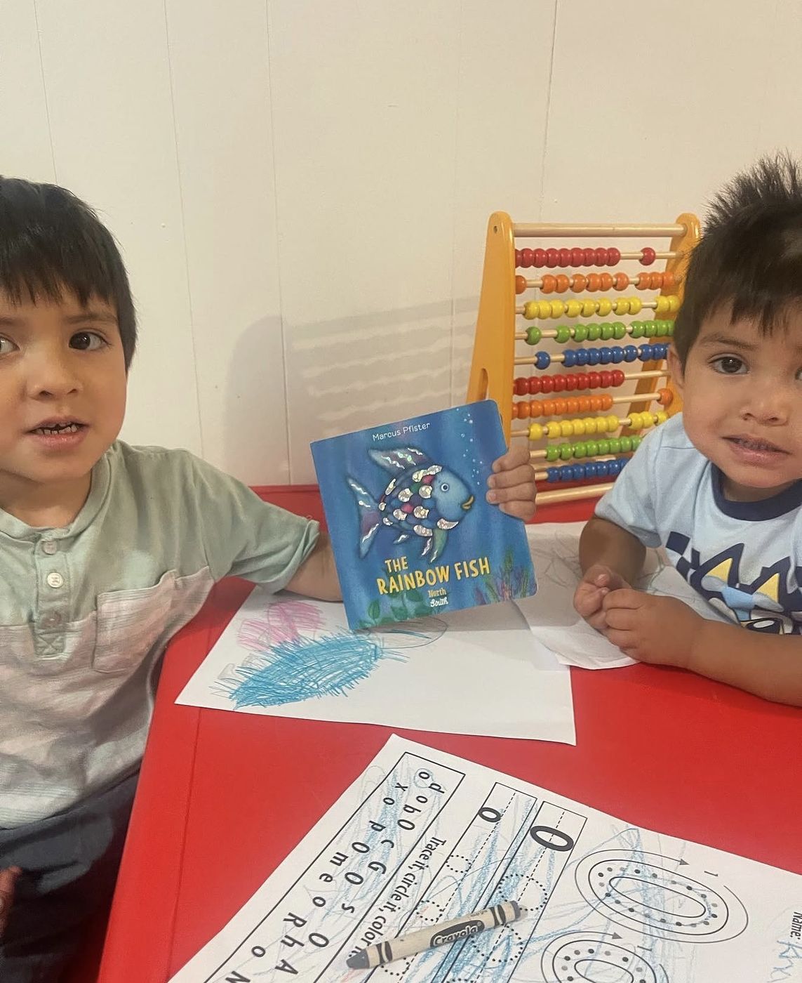 Two boys with The Rainbow Fish book and an abacus
