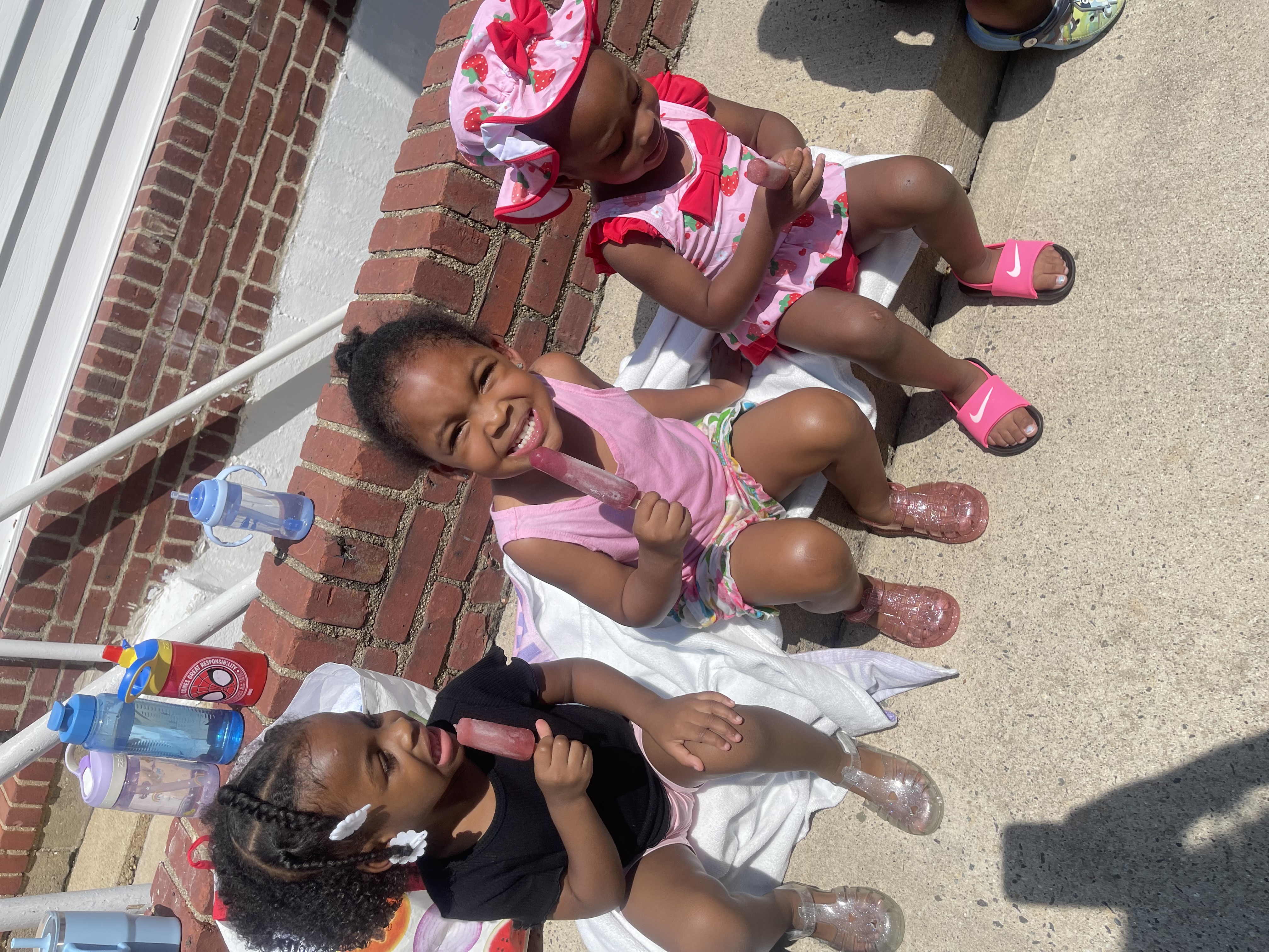 Three girls enjoying popsicles together on a summer day